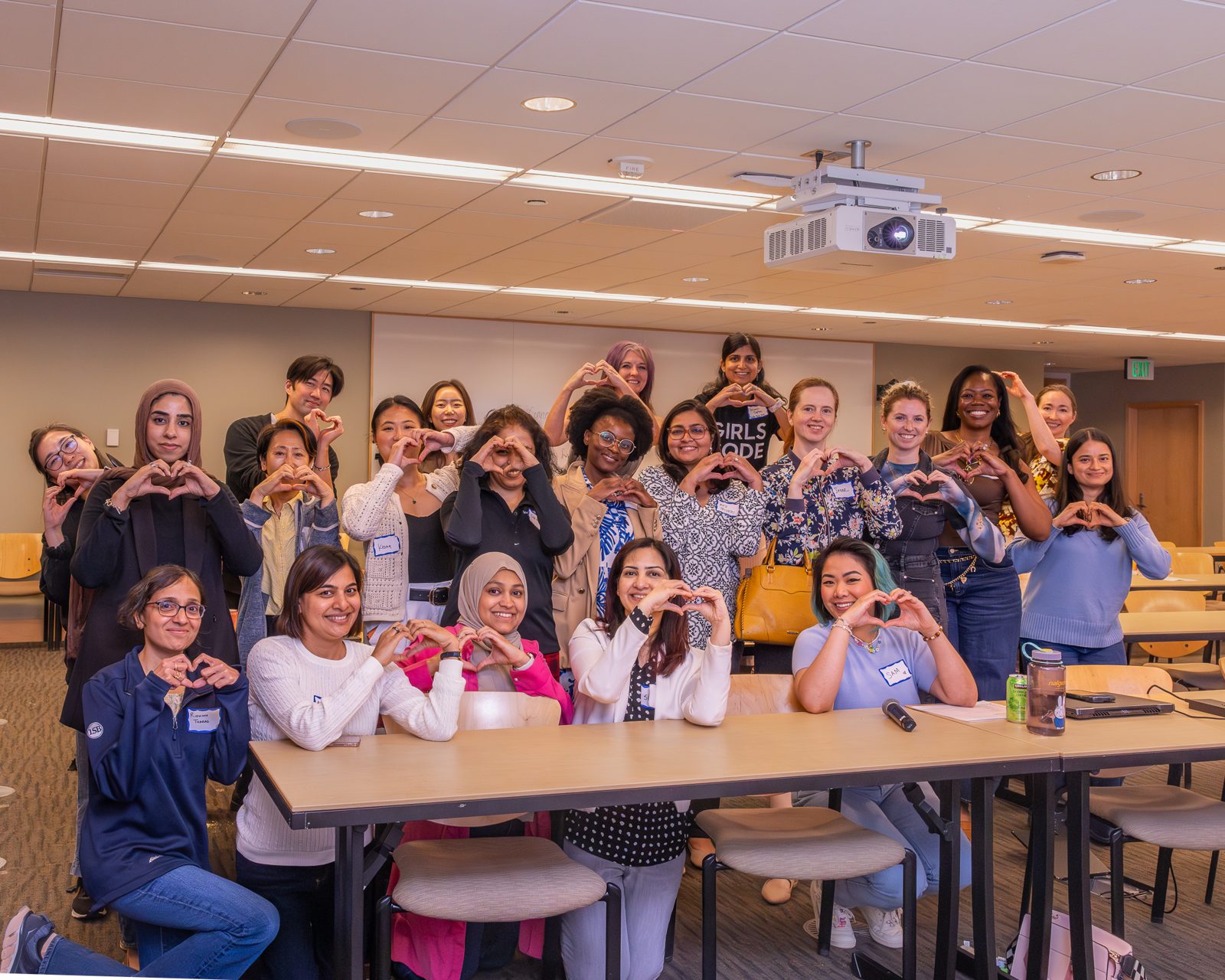 A room full of mothers making heart shapes with their hands at Bellevue City Hall