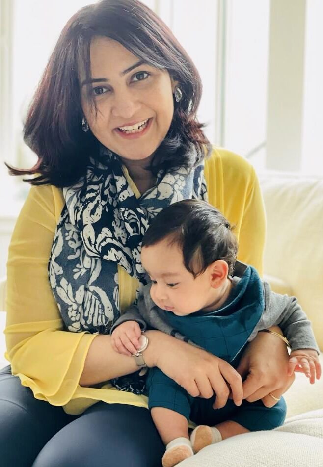 The founder of Moms Who Build holding her baby on her lap, both smiling